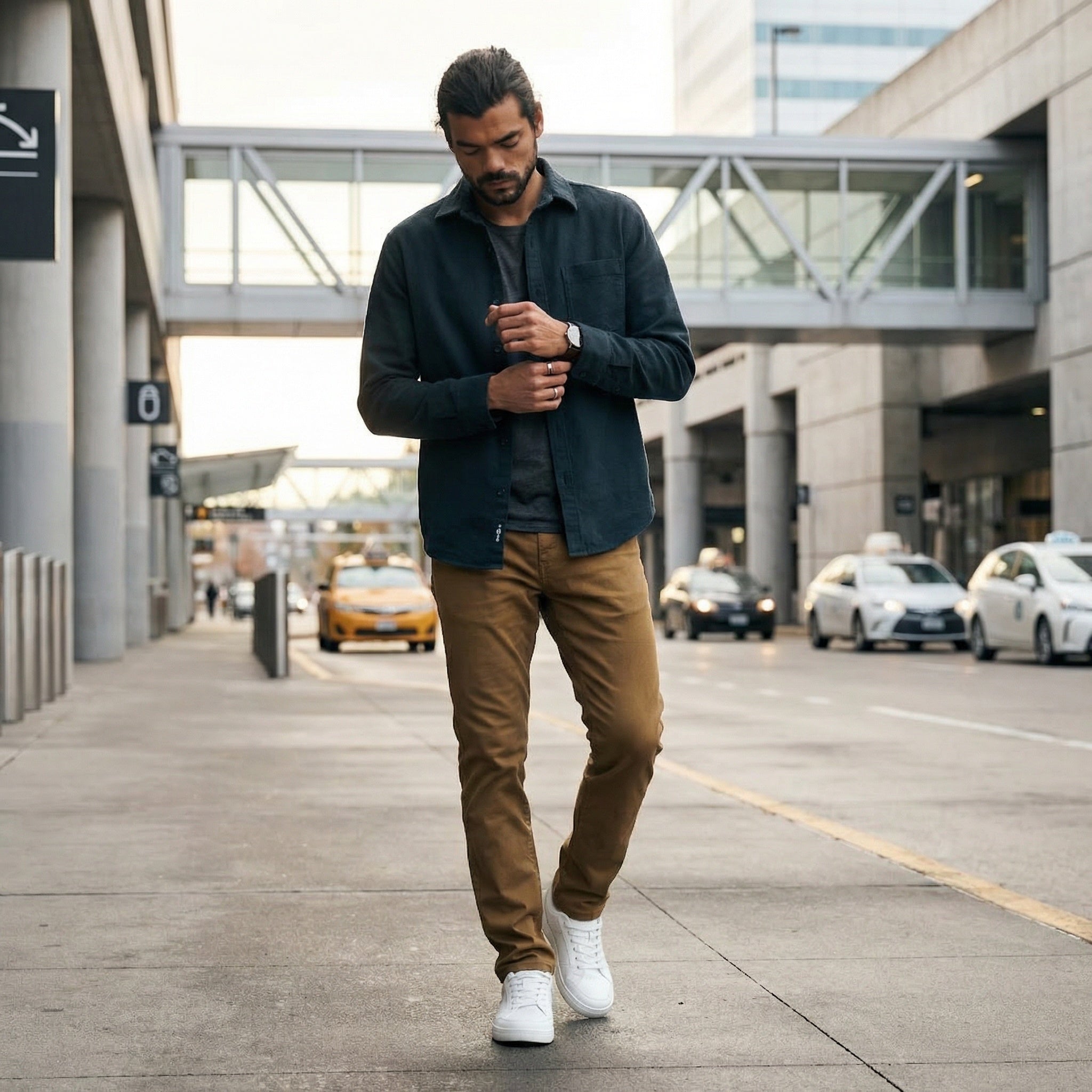 Man walking on a city street wearing a dark shirt, brown pants, and white shoes.