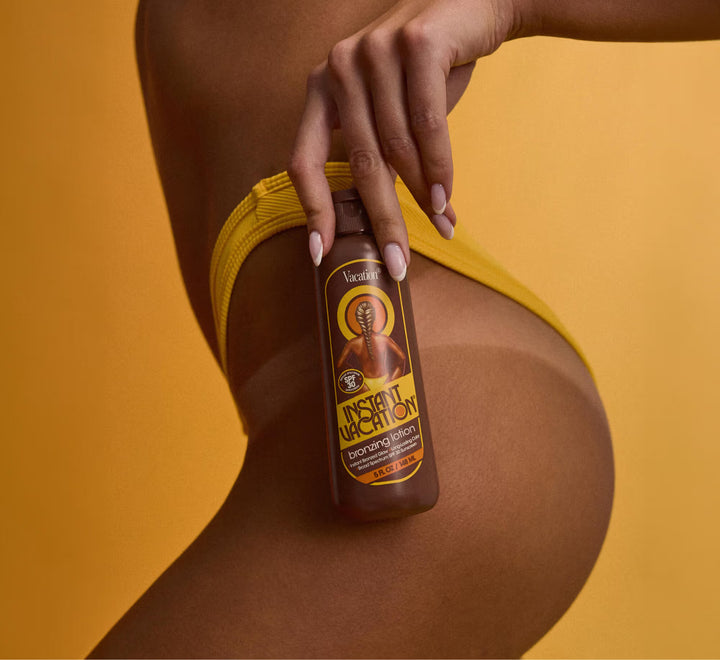Hand holding a bottle of 'Instant Uv Tan' against a yellow background