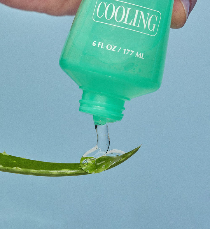 Green bottle labeled 'Cooling' with liquid being dripped onto a leaf against a light blue background