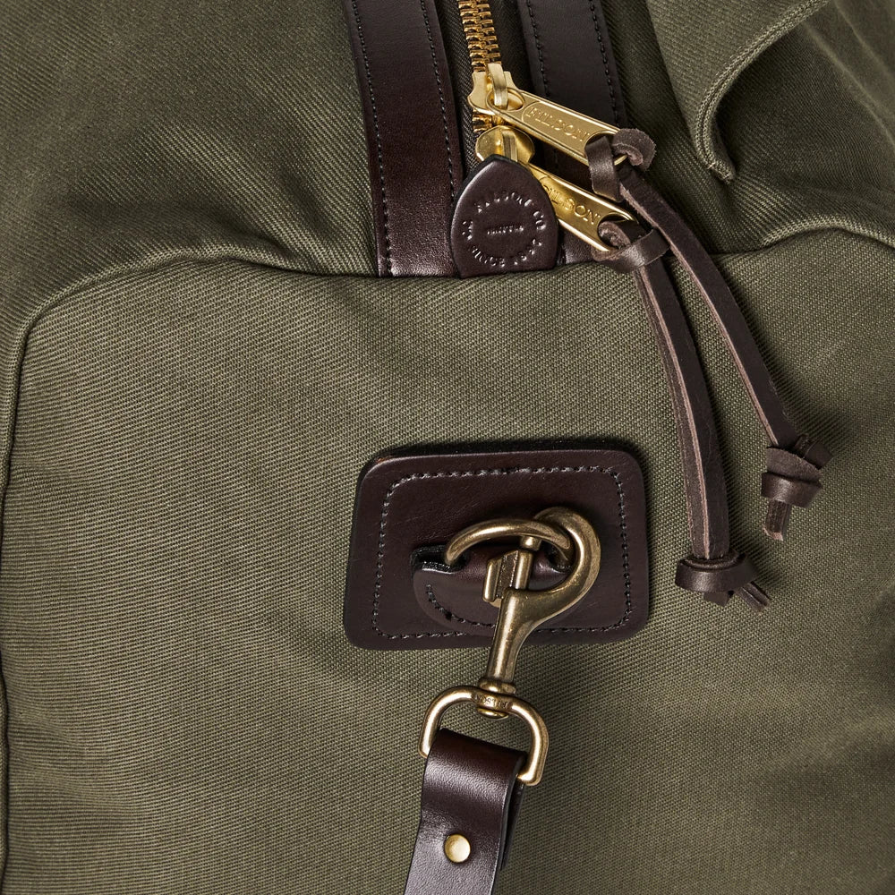 Close-up of a green bag with leather strap and gold zipper