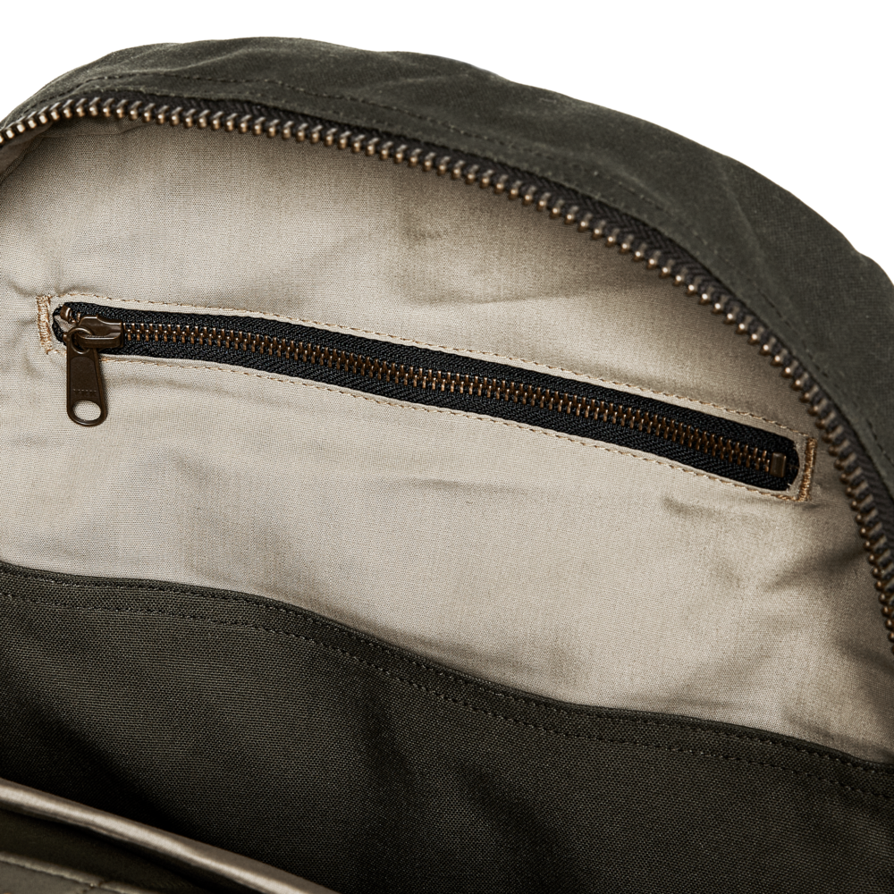 Close-up of a dark olive green bag showing the interior with a beige fabric lining and a dark zipper pocket.