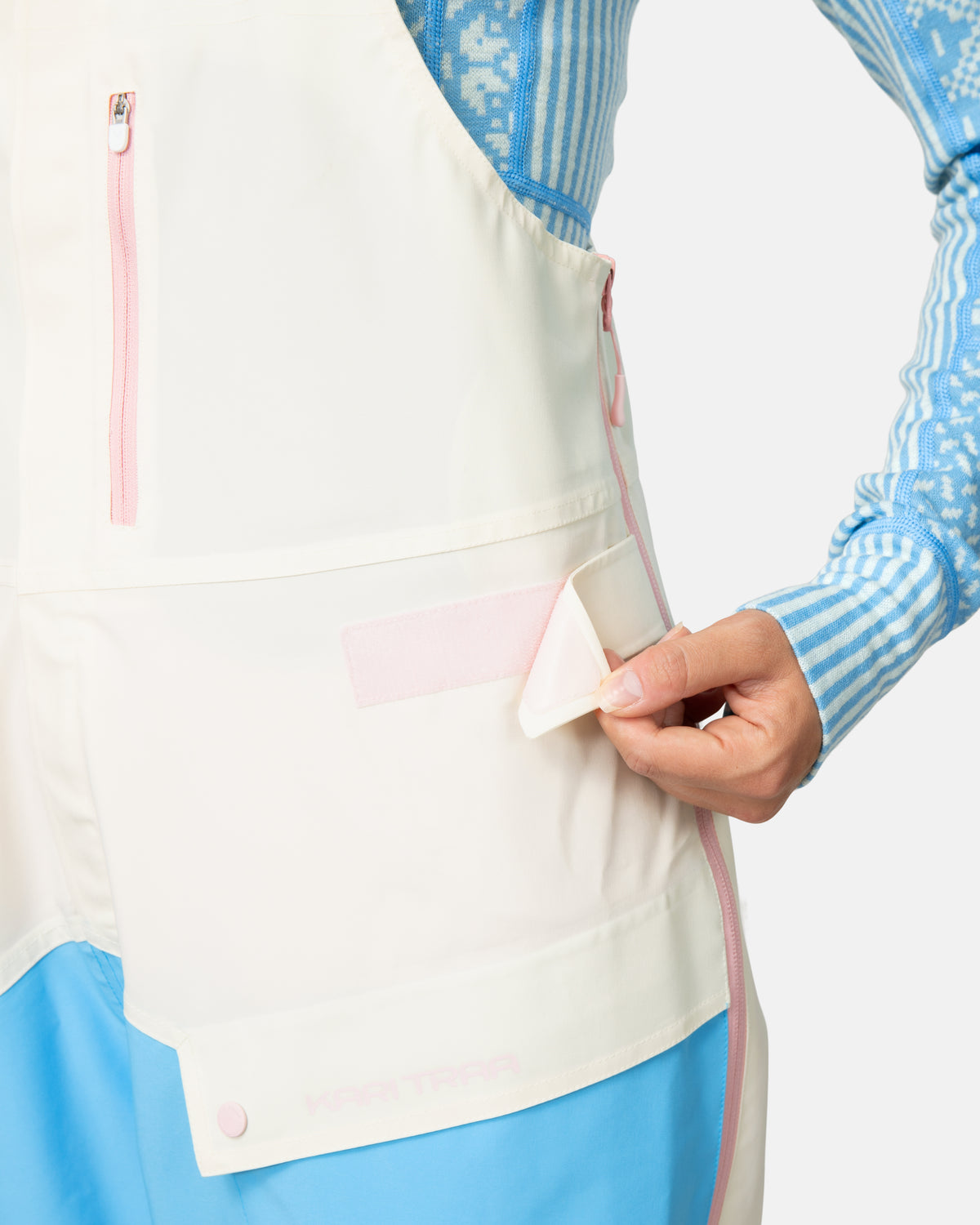 Person wearing a colorful outfit with a white apron, holding a small object.