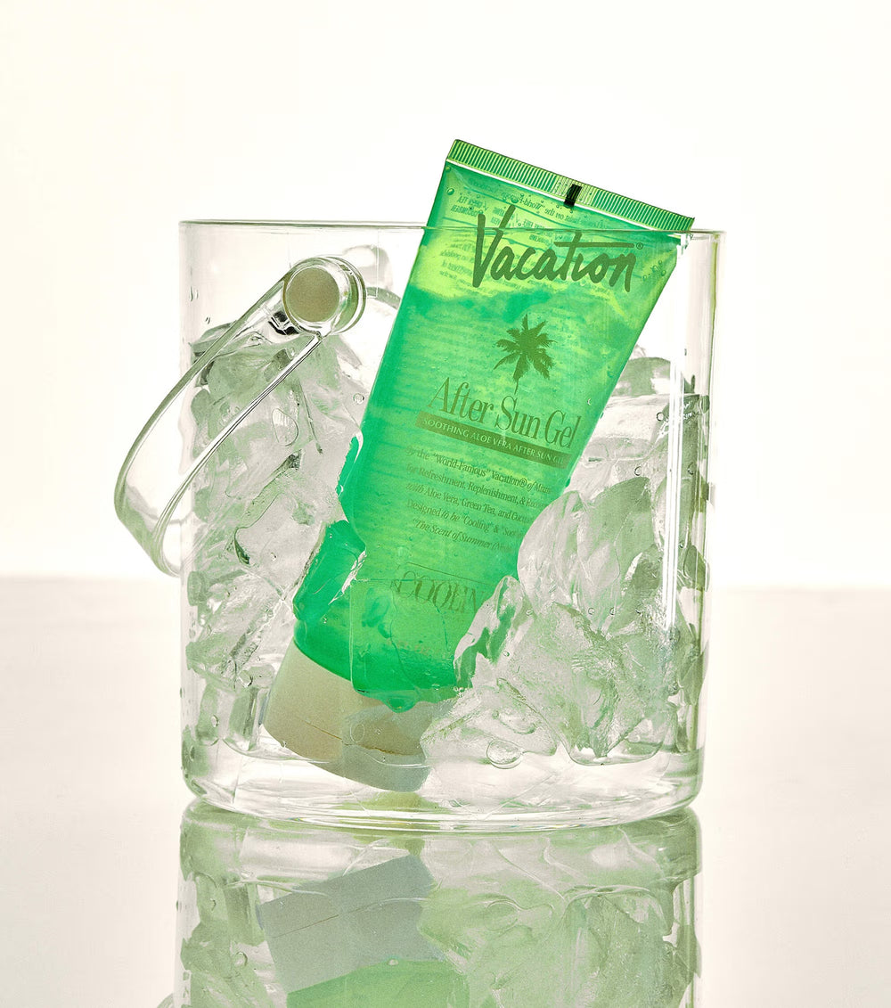 Green tube of 'Vacation' after sun gel in a glass filled with ice on a white background