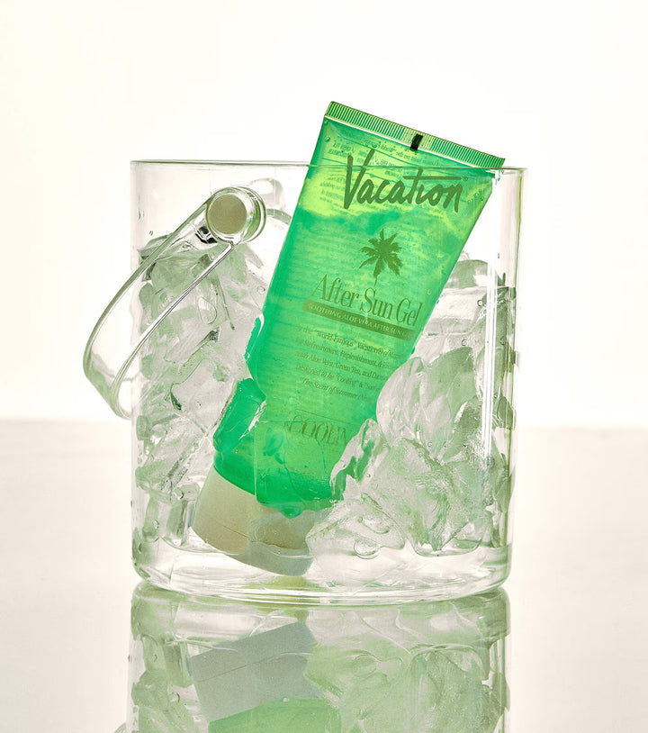 Green tube of 'Vacation' after sun gel in a glass filled with ice on a white background