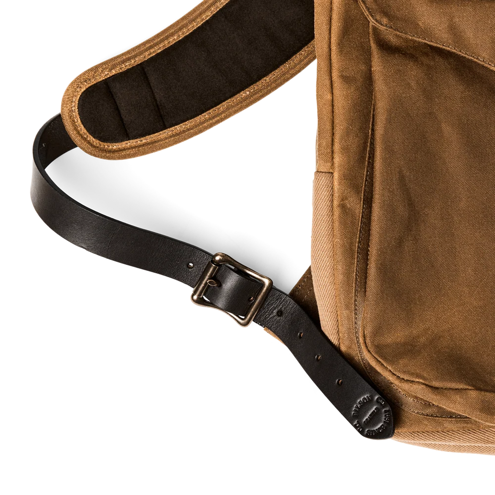 Close-up of a brown canvas shoulder bag with a black adjustable leather strap and metal buckle, shown on a white background.