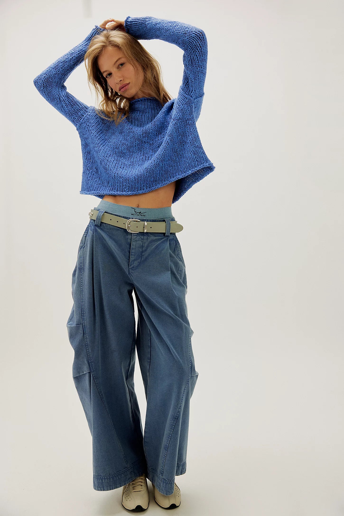 Person wearing a blue knitted sweater and blue pants on a white background