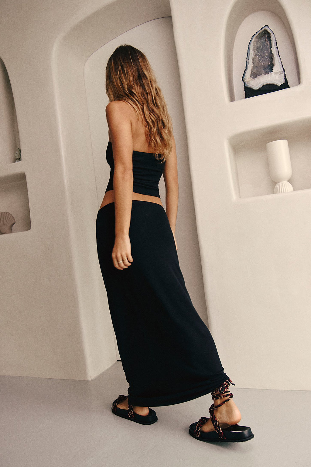 Woman in a black dress standing in a modern architectural setting.