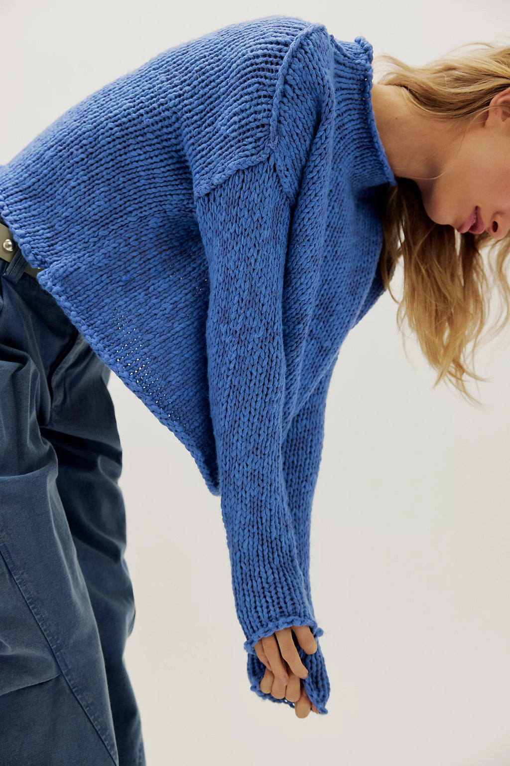 Person wearing a blue knitted sweater with a plain background