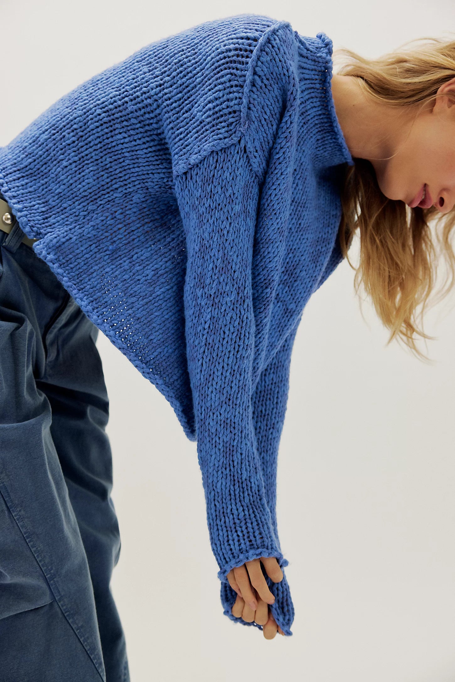 Person wearing a blue knitted sweater with a plain background