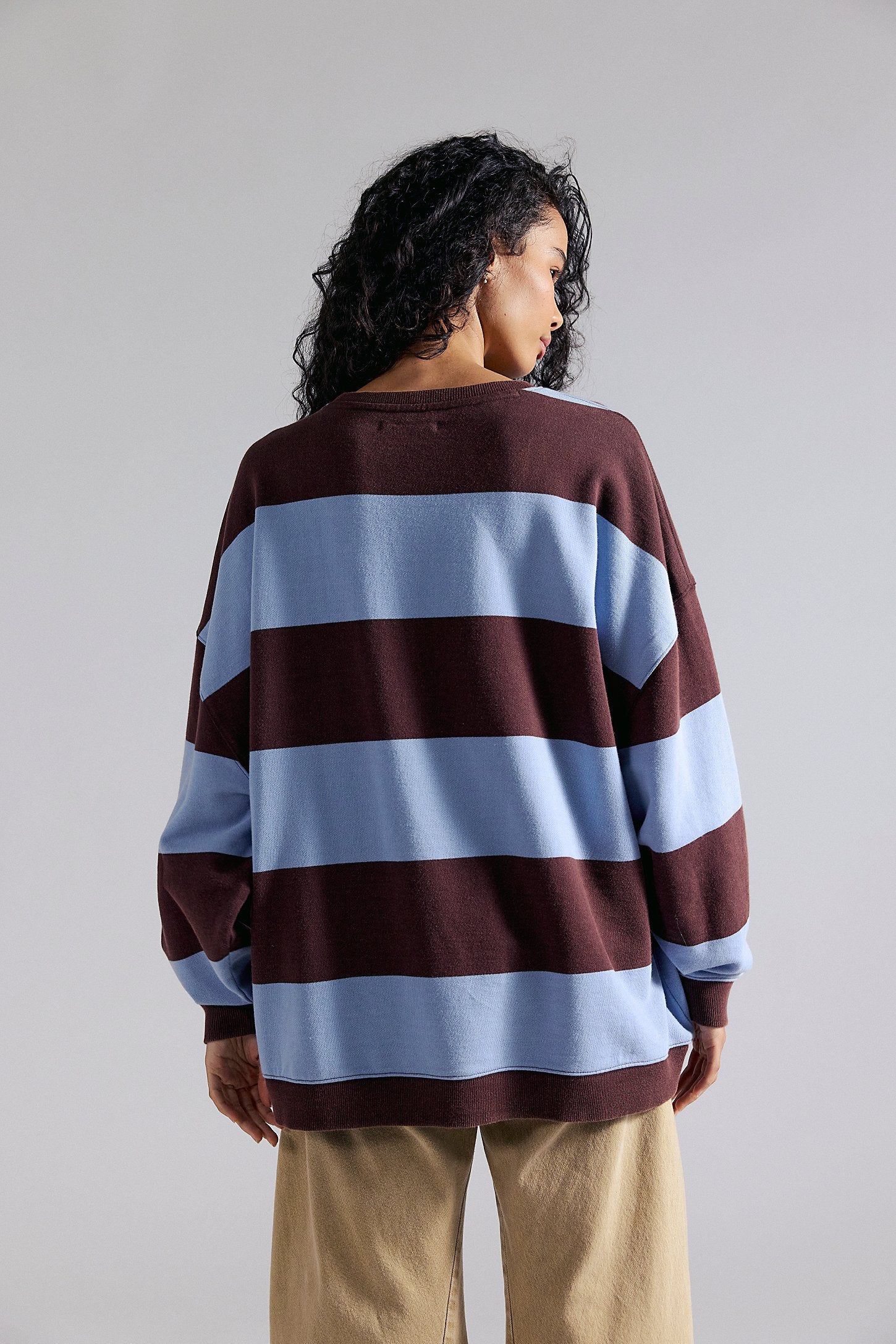 Person wearing a brown and blue striped sweater against a plain background