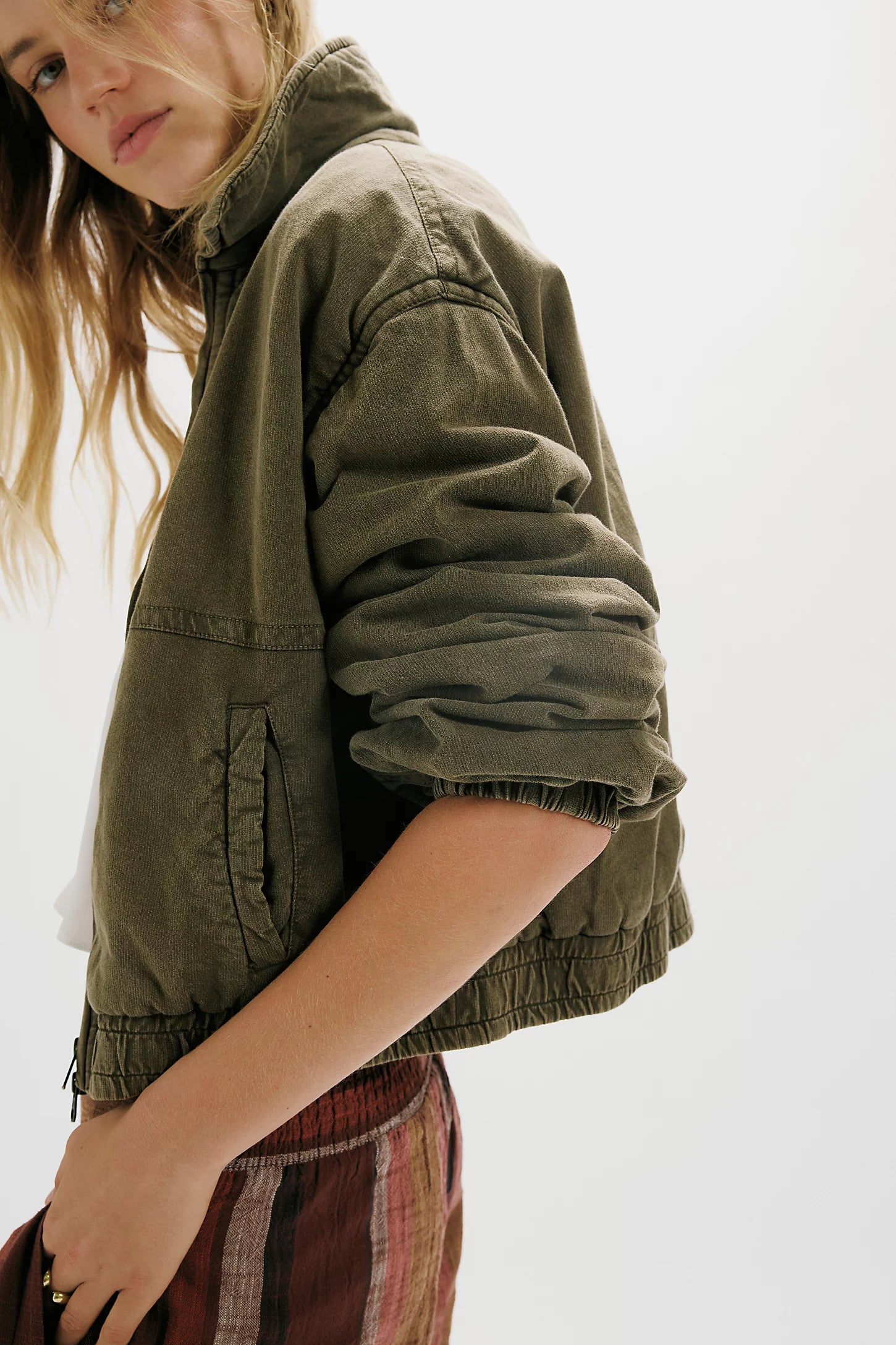 Woman wearing a green jacket and patterned skirt on a white background