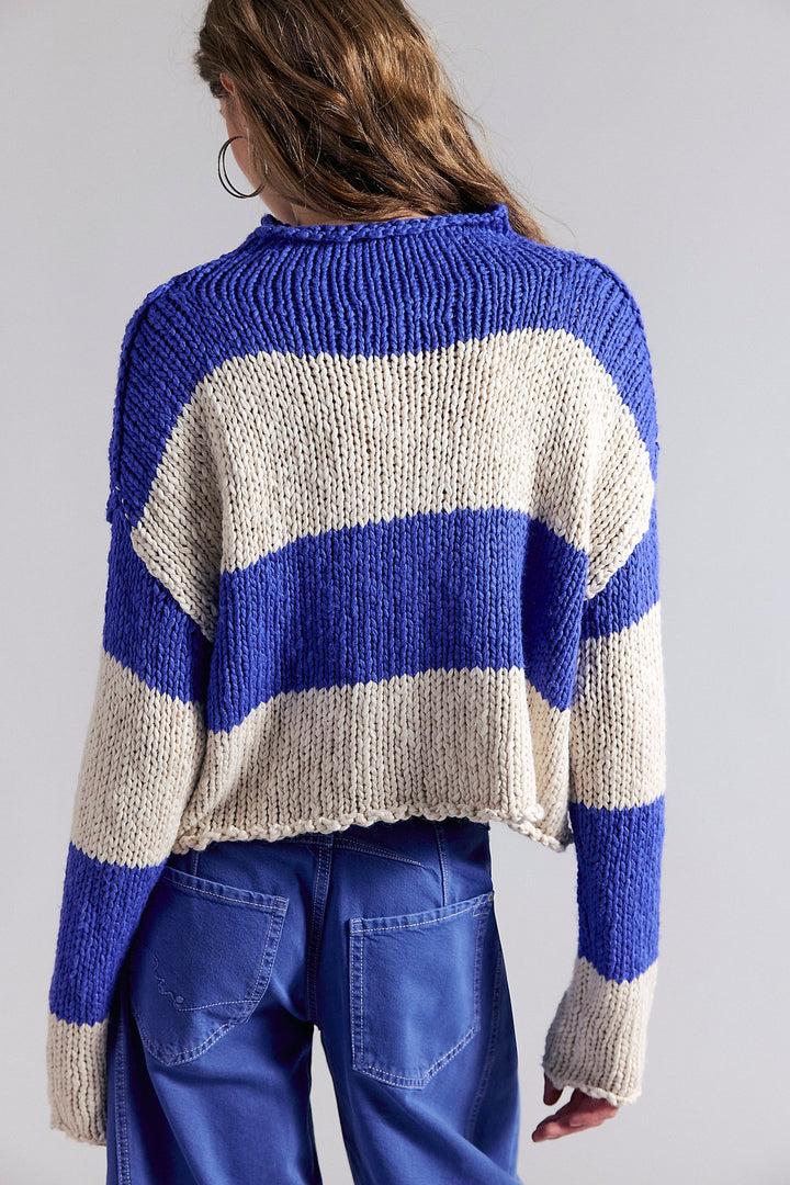 Person wearing a blue and beige striped sweater on a plain background