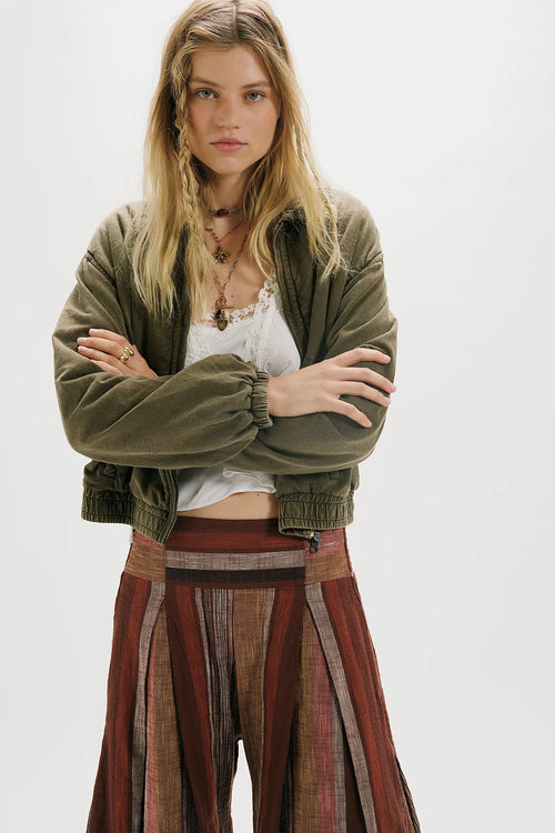 Woman wearing a green jacket and patterned skirt on a white background