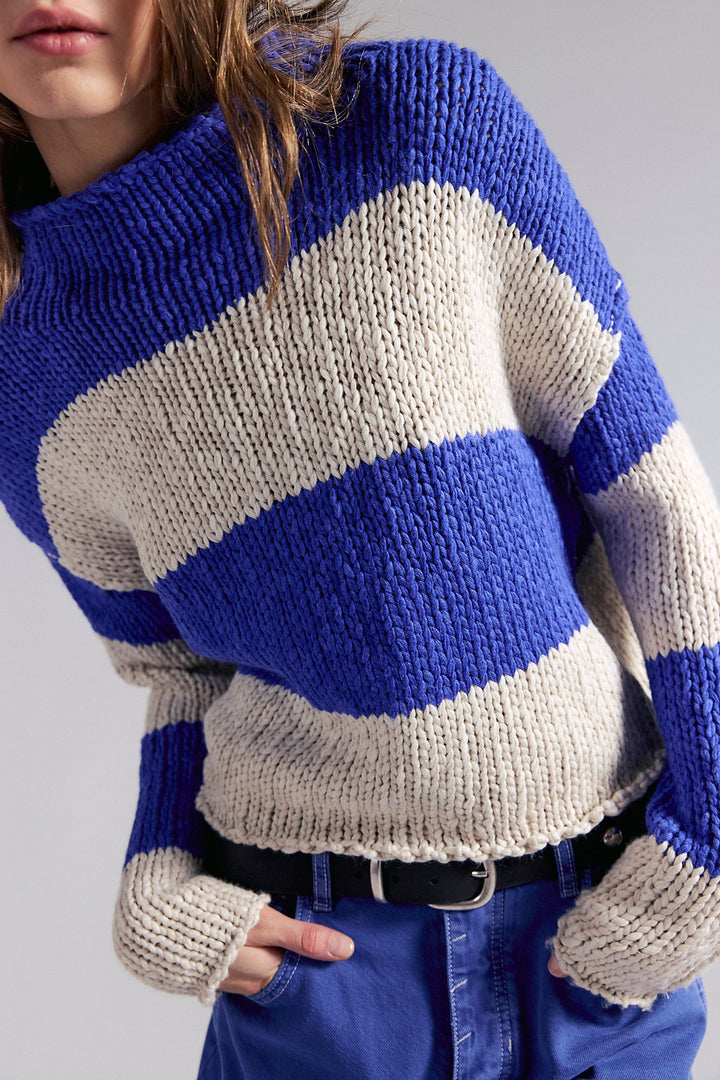 Person wearing a blue and beige striped sweater against a plain background