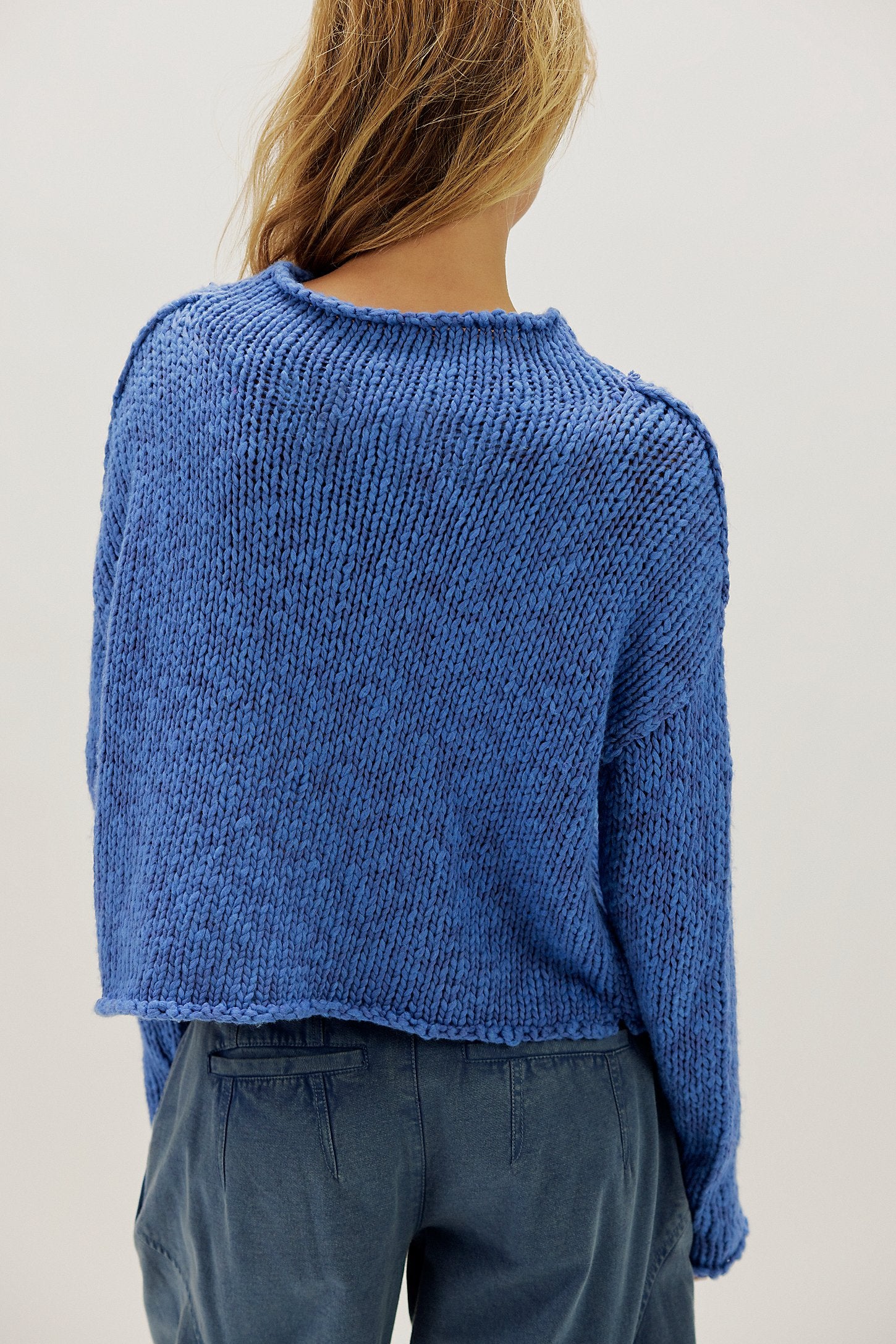 Person wearing a blue knitted sweater against a plain background