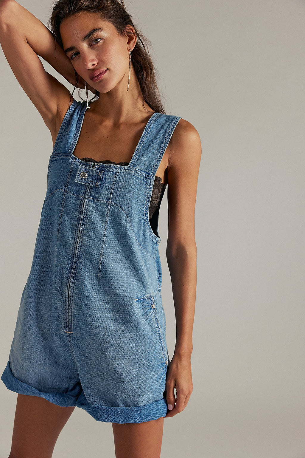 Woman wearing a denim overall romper against a plain background