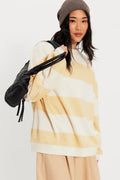 Woman wearing a yellow and white striped sweater with a black backpack on a white background