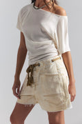 Person wearing a white off-shoulder top and beige shorts on a plain background