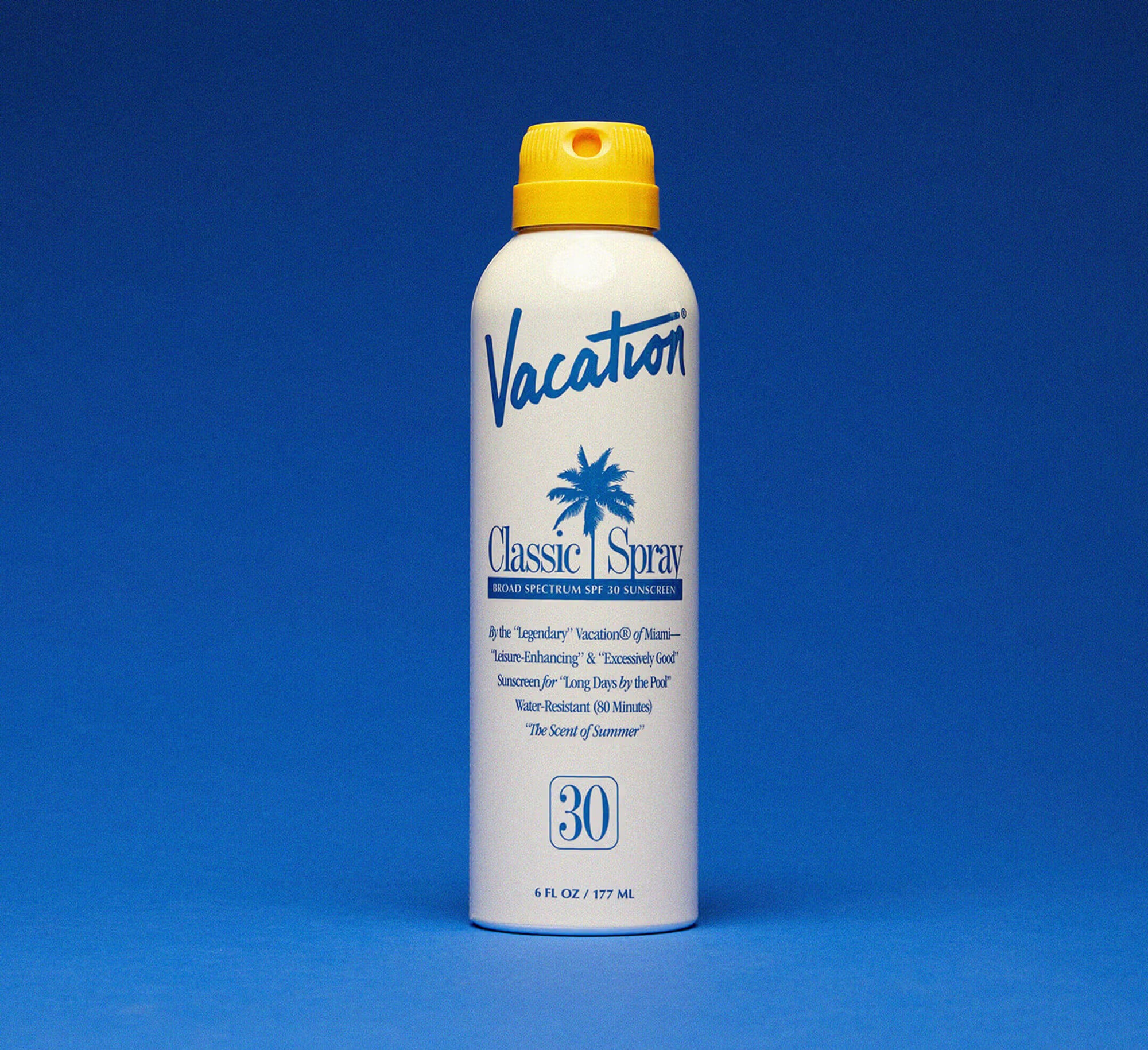 Vacation Classic Spray sunscreen bottle with yellow cap on a blue background