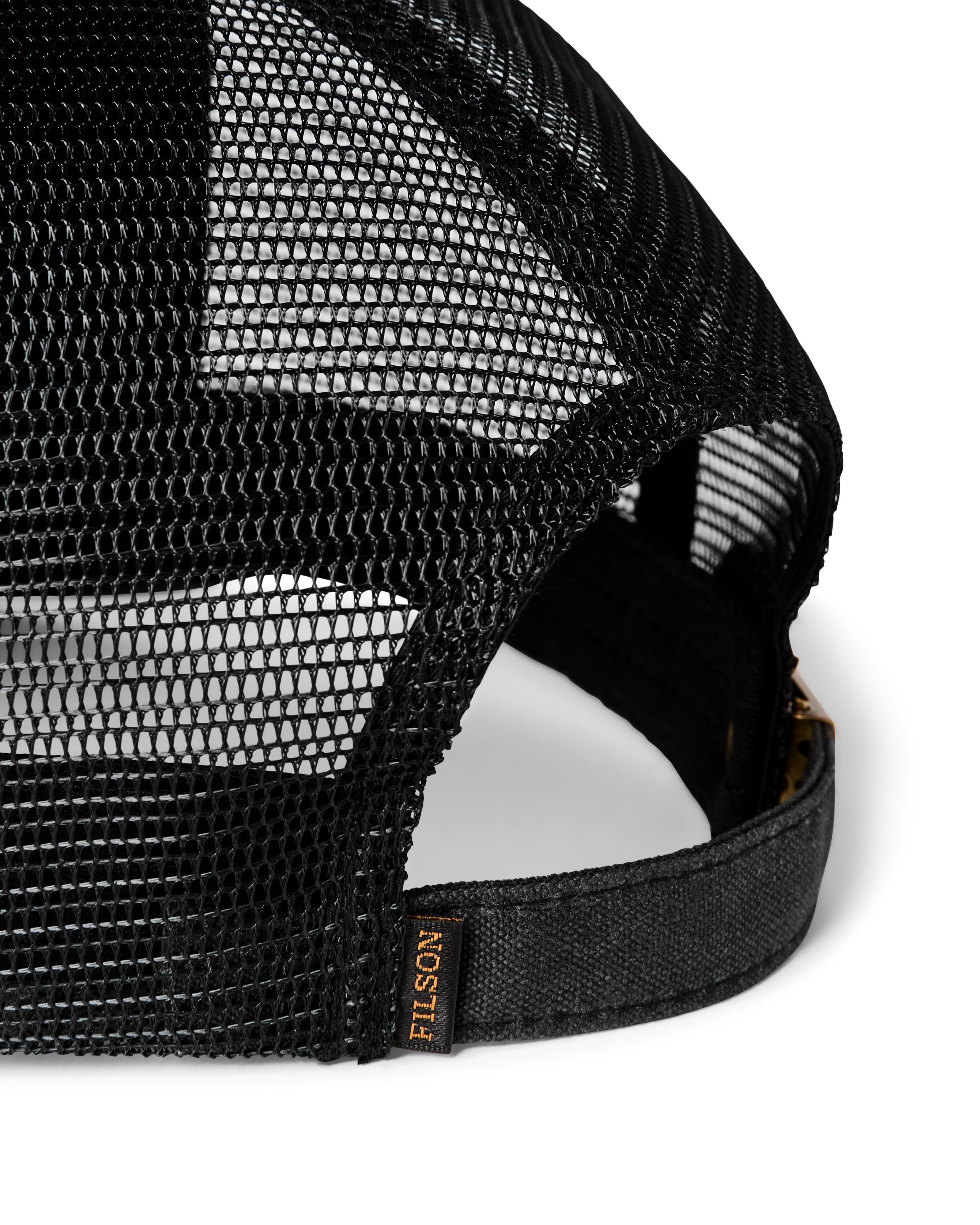 Close-up of a black mesh trucker cap showing the back panels, adjustable strap, and a small FILSON brand tag on the side.