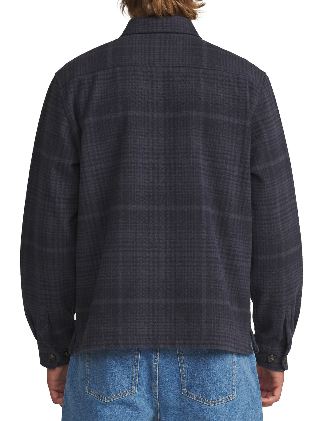 Back view of a person wearing a dark charcoal gray plaid button-down shirt with blue jeans, shown against a plain white background.