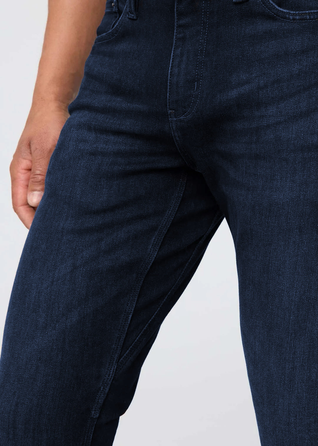 Dark blue jeans with rolled-up cuffs and gray sneakers on a white background