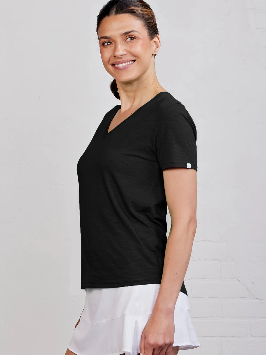 Woman wearing a black t-shirt and white skirt against a light gray background
