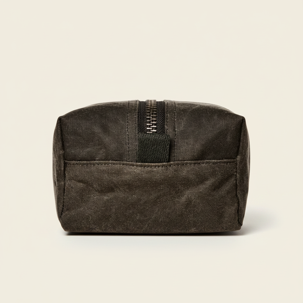 A dark brown waxed canvas zippered pouch with a black zipper pull tab, shown against a plain white background.